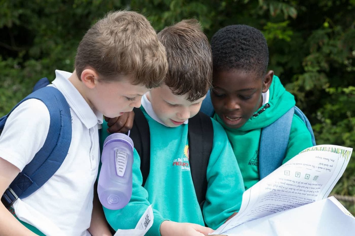 Three young children reading a worksheet from the education trail.
