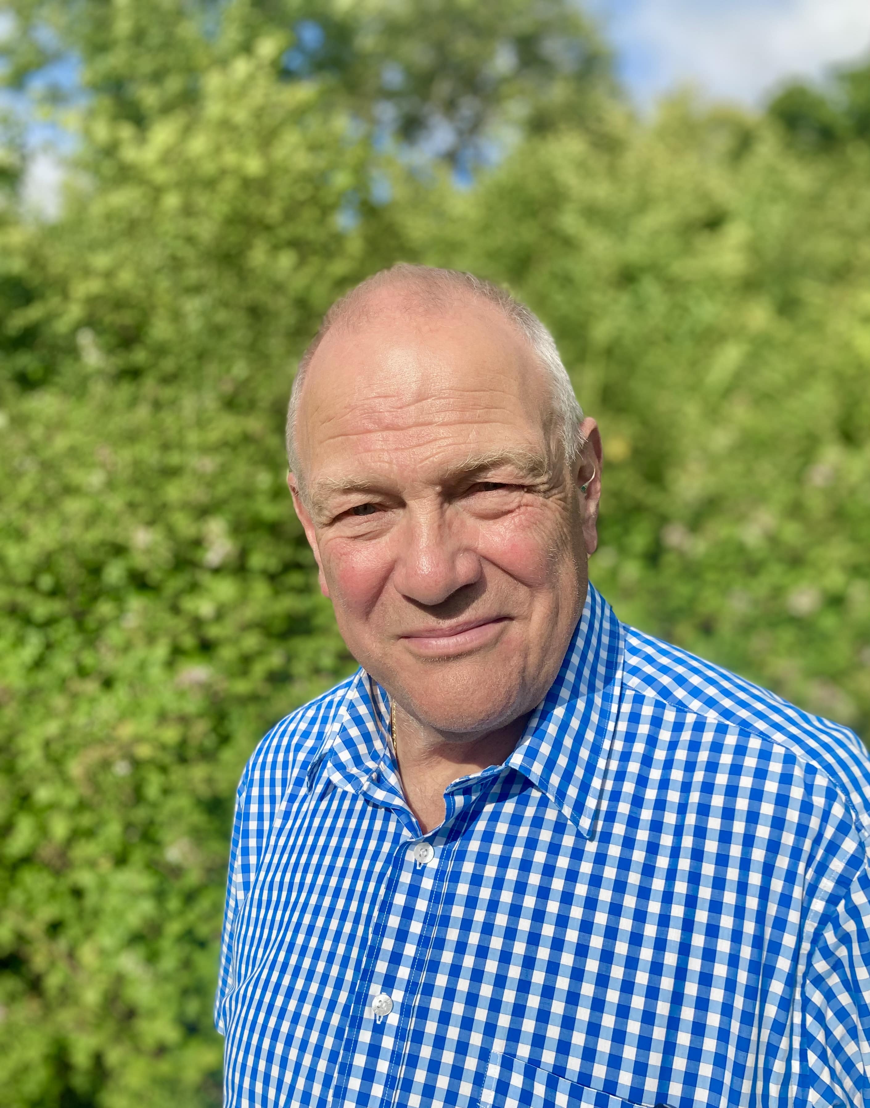 Head shot of Chris Booy against a backdrop of greenery