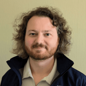 A headshot of a man with curly hair and a beard