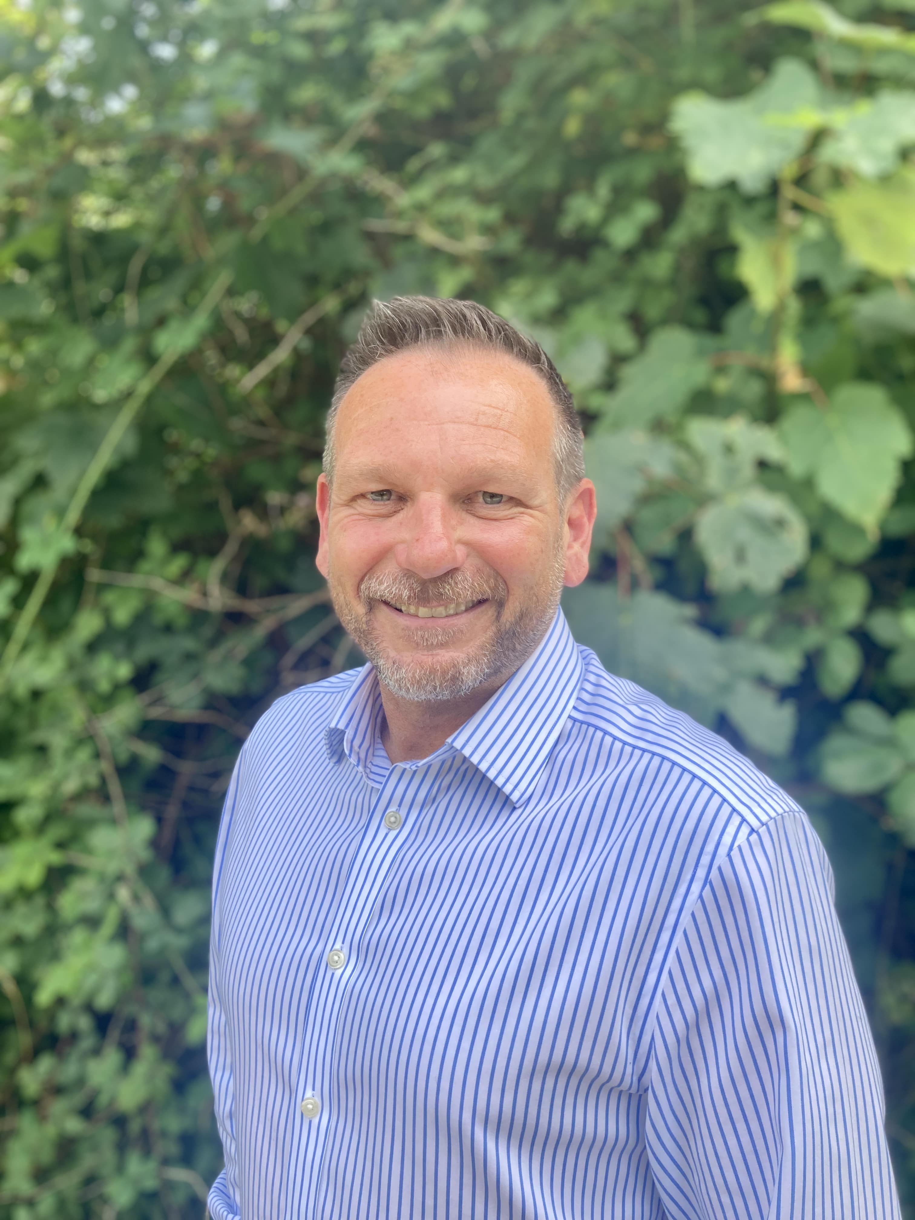 Jonathan Timney standing in front of a backdrop of greenery